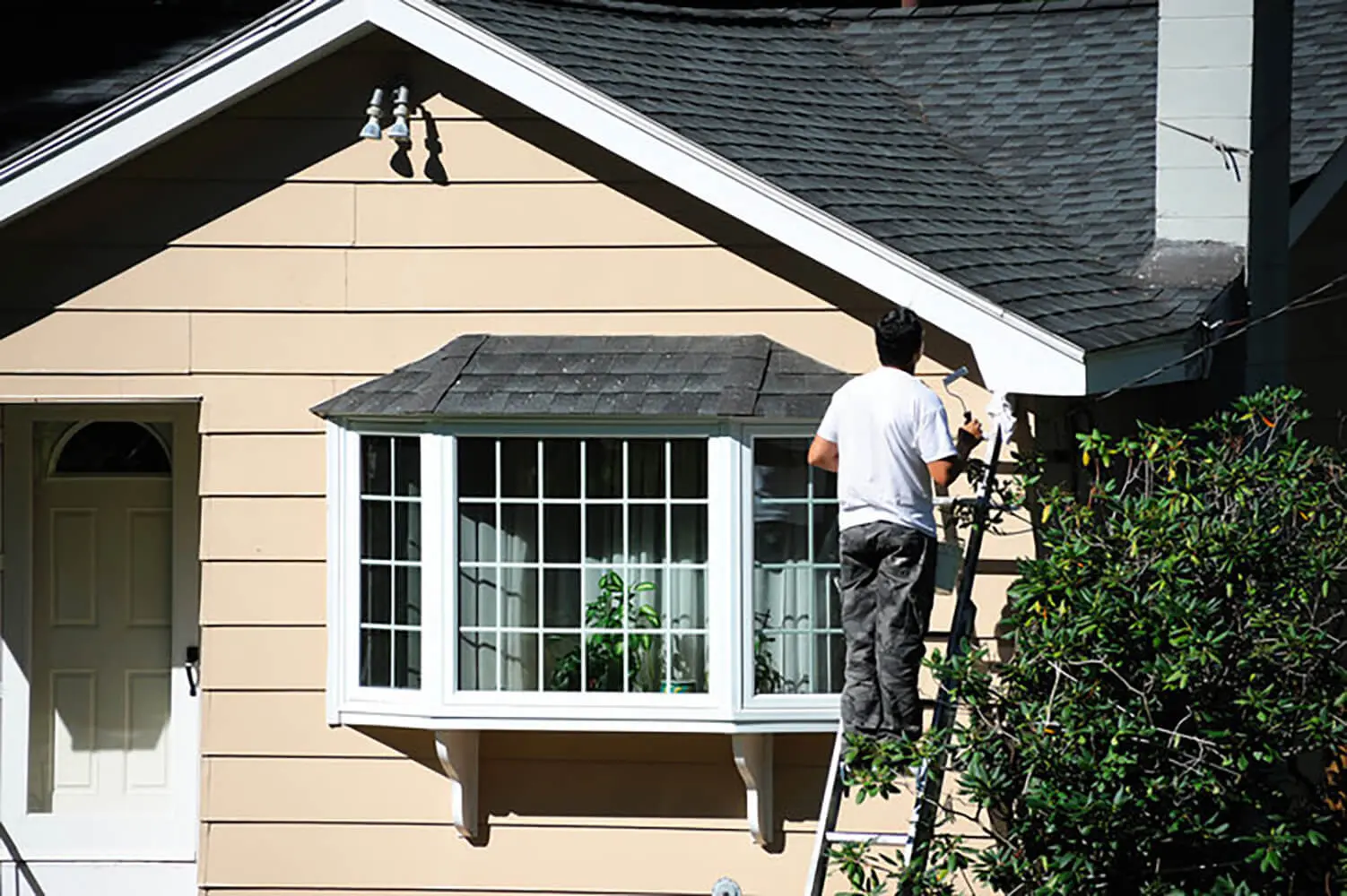 Painter working on the exterior of a residential home during the best time for exterior house painting in Pittsburgh