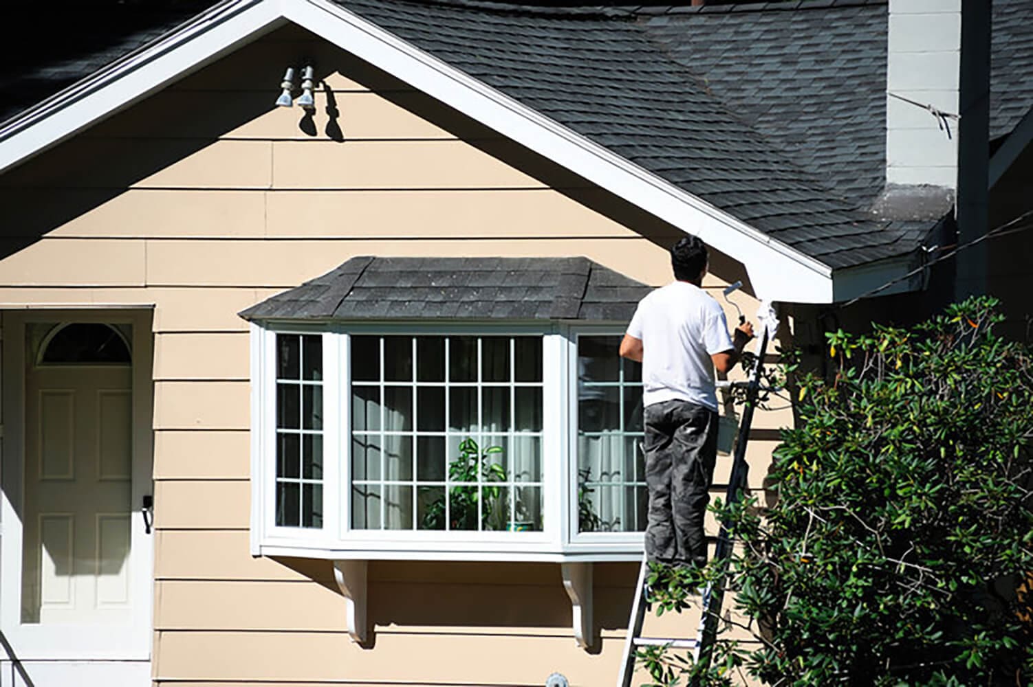 Painter working on the exterior of a residential home during the best time for exterior house painting in Pittsburgh