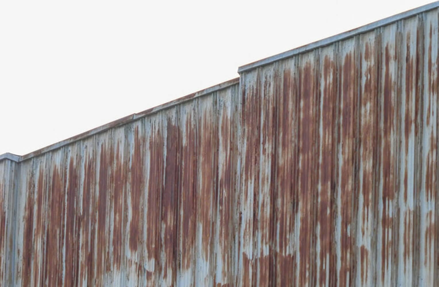 Rusted corrugated metal siding on an industrial facility showing signs of coating failure and corrosion