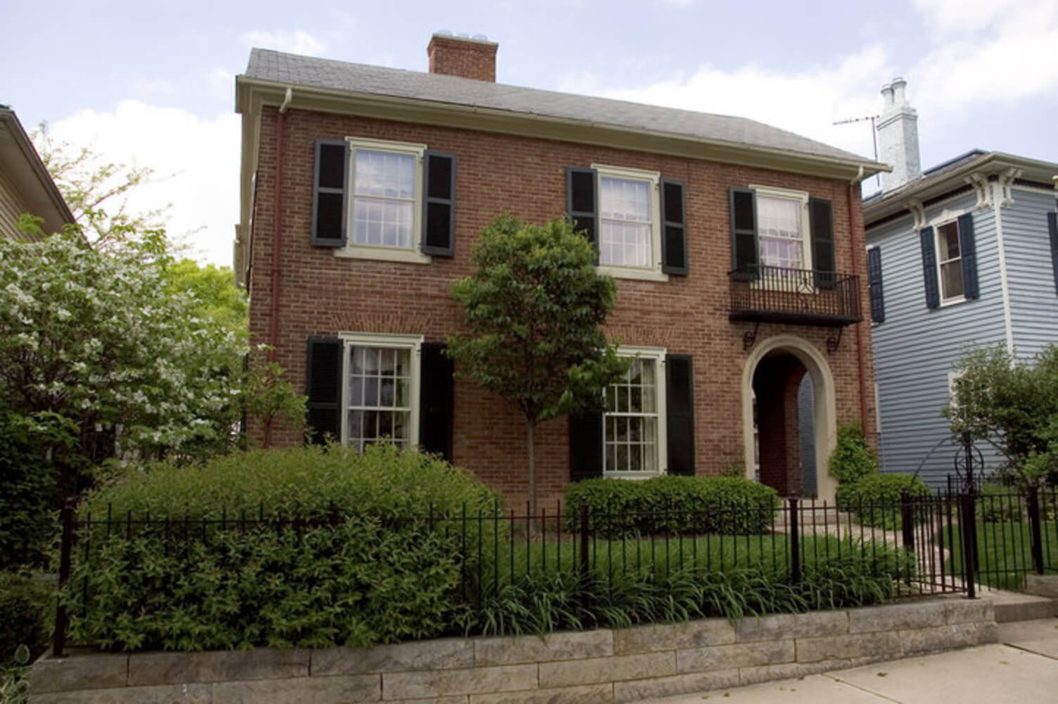 A traditional two-story brick home exterior, the type of surface homeowners weigh when comparing brick staining vs painting.
