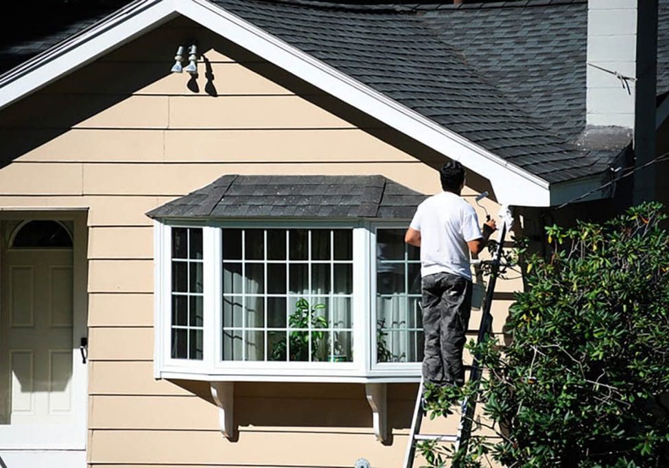 Painter working on the exterior of a residential home during the best time for exterior house painting in Pittsburgh